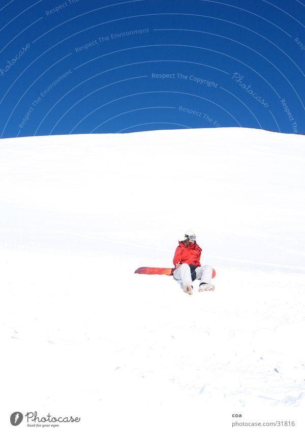 Pause Winter weiß rot Snowboard ruhig hocken Sport Schnee blau Himmel sitzen Snowboarder Wolkenloser Himmel leuchtende Farben Schönes Wetter 1 Winterstimmung