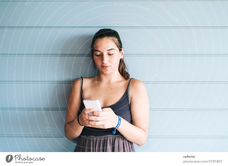 Schöne junge Frau, die sich mit einem Smartphone an die Wand lehnt. Lifestyle Glück schön Sommer Telefon Handy PDA Technik & Technologie Mensch feminin