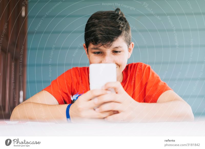 Junge im roten T-Shirt, der im Freien sitzt und telefoniert. Lifestyle Glück Freizeit & Hobby Telefon Handy PDA Technik & Technologie Mensch maskulin Mann