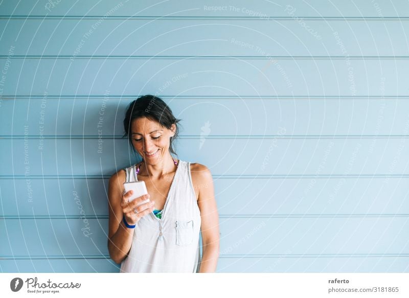 Schöne Frau, die sich an die Wand lehnt, während sie das Smartphone benutzt. Lifestyle Glück schön Sommer Telefon Handy PDA Technik & Technologie Mensch feminin