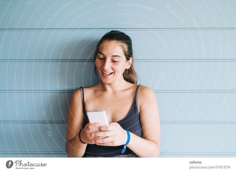 junge Frau, die sich an eine Holzwand lehnt, während sie ein Smartphone benutzt. Lifestyle Glück schön Sommer Telefon Handy PDA Technik & Technologie Mensch