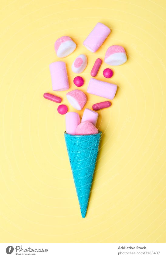 Blauer Waffelkegel mit verschütteten Süßigkeiten Zapfen Süßwaren mehrfarbig Entwurf süß Dessert lecker Stil Konfekt hell blau rosa Feinschmecker Götterspeise