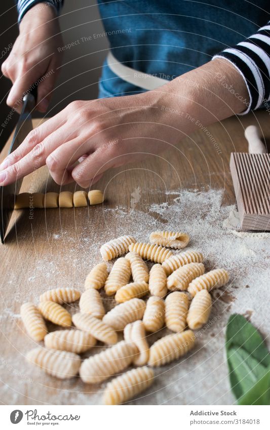 Getreidefrau, die Gnocchetti-Nudeln herstellt. Frau Spätzle Schneiden Teigwaren Vorbereitung Italienisch Tisch Küche gebastelt Tradition roh Lebensmittel