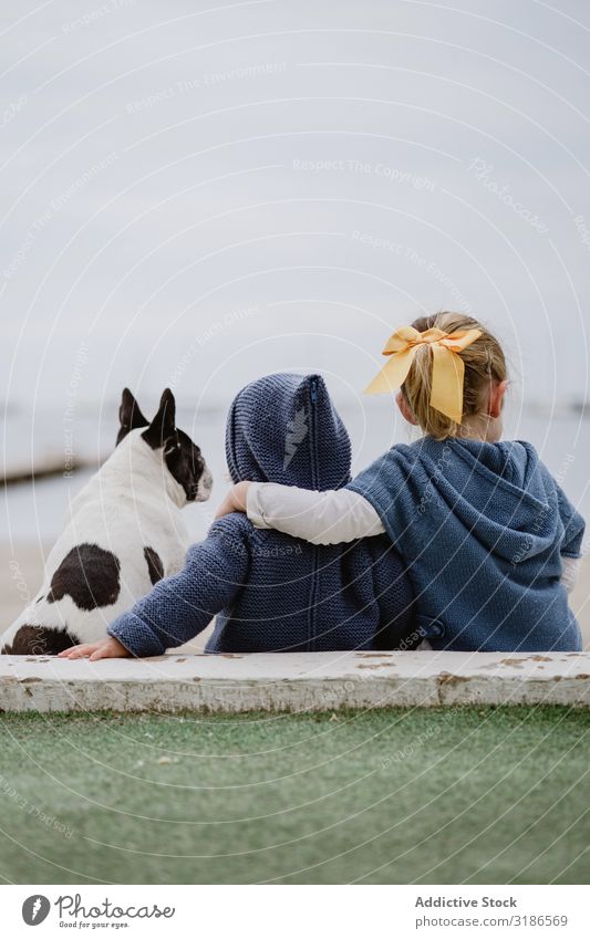 Kinder umarmender Hund am Strand Freundschaft Liebe Umarmen Haustier Meer sitzen gehorsam Baby französische Bulldogge lässig Lifestyle Freizeit & Hobby ruhen