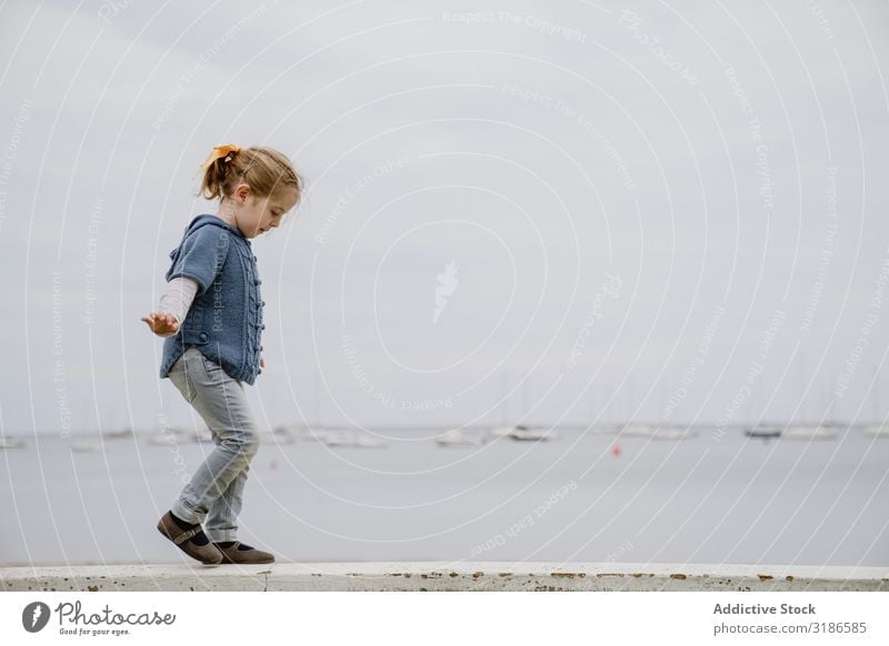 Mädchen balanciert an der Grenze zum Meer Gleichgewicht laufen Küste ausgestreckte Arme klein Lifestyle Freizeit & Hobby Kind lässig Wasser Strand matt Stimmung