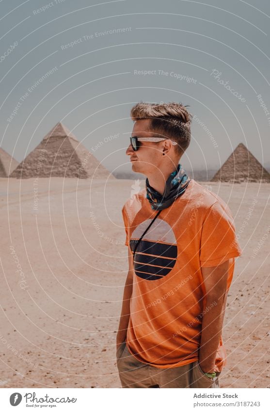 Junger Mann gegen große Pyramiden Reisender Ägypten Gizeh Kairo Jugendliche Wüste Wegsehen Berühmte Bauten Himmel Schönes Wetter Ausflug Tourismus Abenteuer