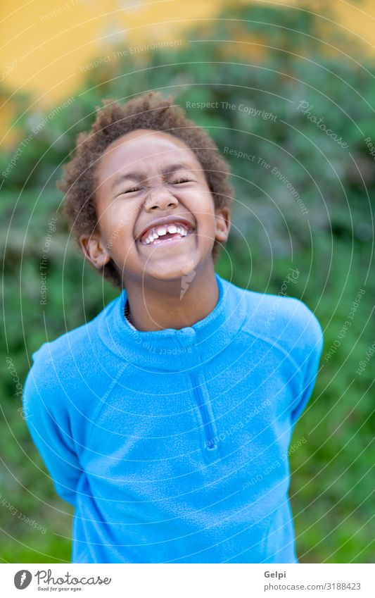Glückliches afrikanisches Kind mit blauem Trikot Freude Erholung ruhig Freizeit & Hobby Spielen Garten Junge Kindheit Herbst Park Wiese Afro-Look Lächeln