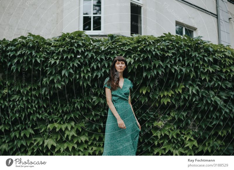 Frau in einem eleganten grünen Kleid steht vor einer Hecke Erwachsener attraktiv schöne Frau charmant schick Großstadt klassisch Bekleidung selbstbewusst Europa