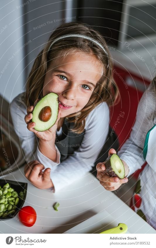 Kleines Mädchen mit geschnittener Avocado zeigen Hälfte Küche reif Kind kochen & garen Gesundheit Diät heimwärts Frau Samen Lebensmittel grün