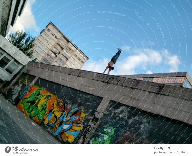 Junger Mann macht einen Handstand an einer hohen Wand Lifestyle Sonne Sport Mensch Erwachsene 1 Himmel Straße Graffiti Bewegung Fitness anstrengen Le Parkour