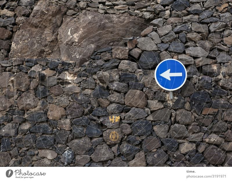 Richtungsvorschlag stein mauer schild verkehrszeichen steine dunkel braun blau links richtung orientierung tageslicht ordnung pfeil