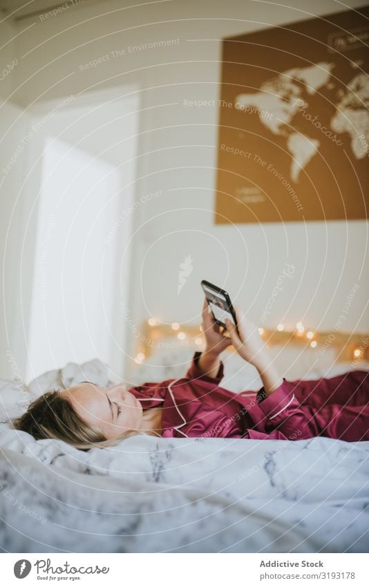 Frau auf dem Bett liegend mit Smartphone Tag Pyjama Morgen Einsamkeit freiberuflich Jugendliche Gerät Freiheit Tablet Computer weiß positiv Kielwasser hübsch