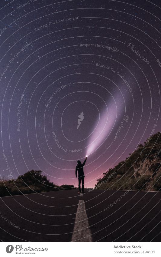 Reisender steht mit Fackel in einer sternenklaren Nacht. Glanz ausleeren Schwebebalken Natur erkunden Stern Erhöhung Silhouette Rochen majestätisch Taschenlampe