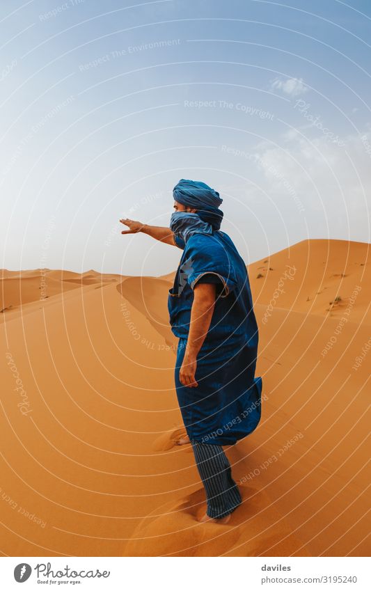 Ein arabischer Mann in blauer Kleidung läuft auf einer Wüstendüne. Lifestyle Ferien & Urlaub & Reisen Tourismus Ausflug Abenteuer Mensch Erwachsene 1