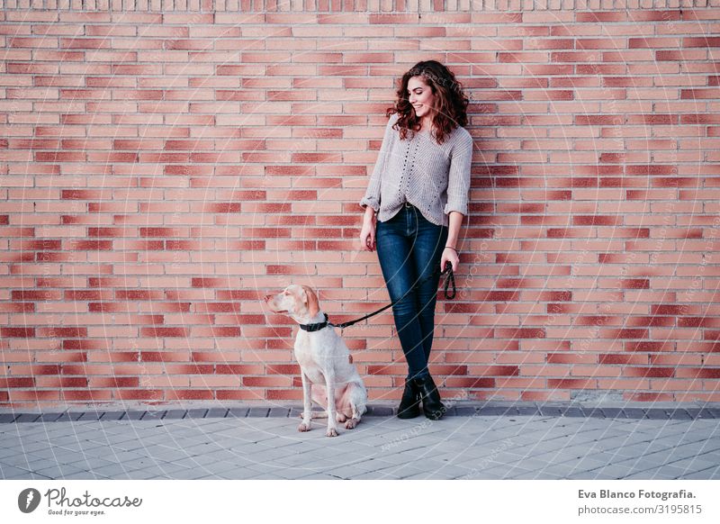 junge Frau und ihr Hund in der Stadt. an einer Ziegelmauer stehend Porträt Park Jugendliche Außenaufnahme Liebe Haustier Besitzer schön Glück Lächeln