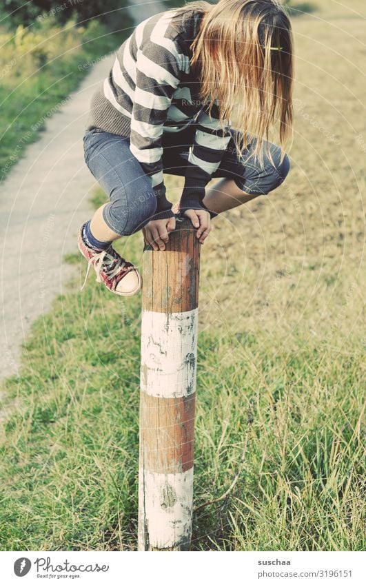 kletterin Kind Mädchen jungennhaft Klettern Spielen gewagt Pfosten Holzpfahl Zaunpfahl festhalten Außenaufnahme Fußweg Natur toben Kindheit Geschicklichkeit
