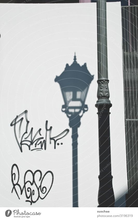schattenzeichnung Schatten Graffiti Gekrakel Zeichnung Schriftzeichen Laterne Straßenbeleuchtung Stadt Stadtleben Sommer Licht & Schatten Laternenpfahl