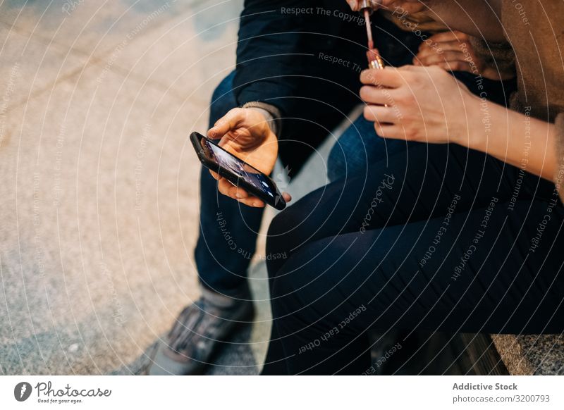 Paare mit Smartphone zusammen auf der Bank benutzend PDA Mitbenutzung sitzen Großstadt Straße Zusammensein interessant Video beobachten Mann Frau Jugendliche