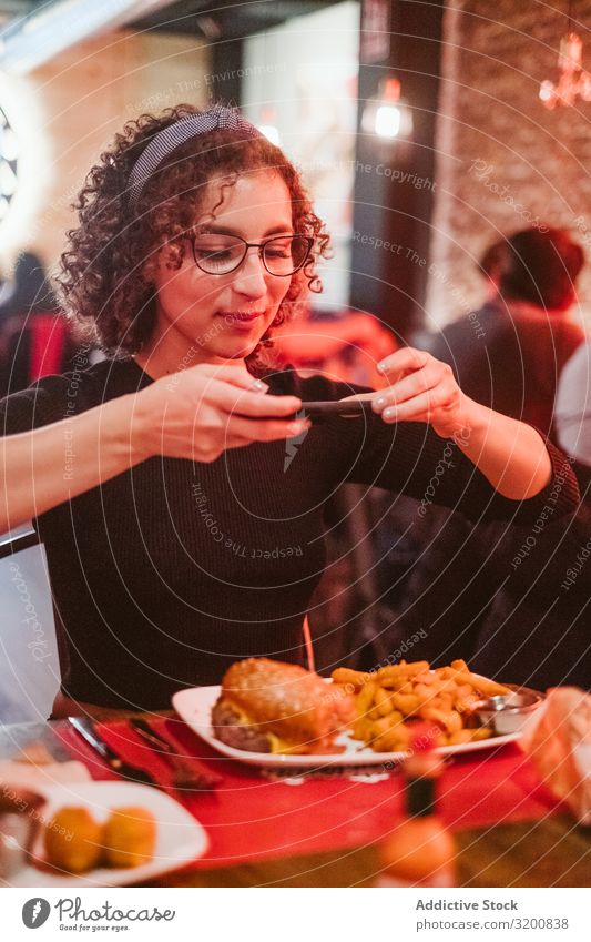 Junge Frau beim Fotografieren von Lebensmitteln PDA Café Burger Pommes frites soziale Netzwerke Lifestyle Freizeit & Hobby sitzen Tisch Technik & Technologie