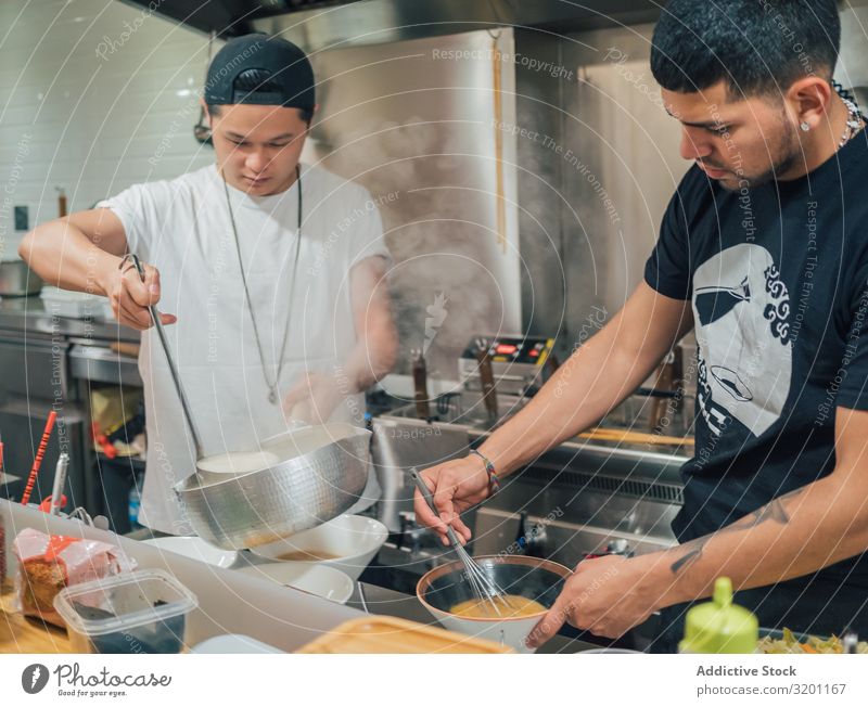 Asiatische Männer, die in der Küche Suppe ausschenken Mann kochen & garen Ramen Topf Lebensmittel Beruf Japaner Speise Restaurant Arbeit & Erwerbstätigkeit