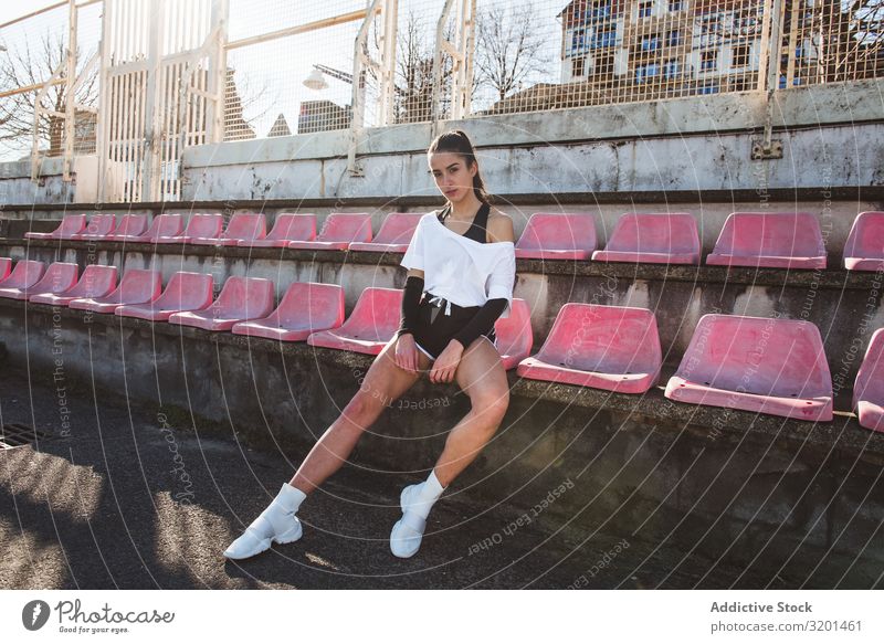 Junge Sportlerin ruht auf schäbigem Sitz Frau Stadion Fitness Pause sitzen Meer ruhen Jugendliche Sportbekleidung Einrichtung verwittert Erholung Athlet