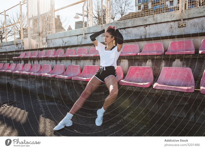 Junge Sportlerin ruht auf schäbigem Sitz Frau Stadion Fitness Pause sitzen Meer ruhen Jugendliche Sportbekleidung Einrichtung verwittert Erholung Athlet