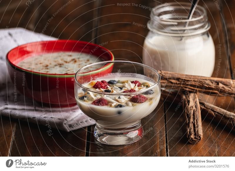 Joghurt in Glasschüssel mit Beeren und Zimtstäbchen Himbeeren Johannisbeeren Flocken Hafer duftig natürlich Vegane Ernährung vegane Milch Lebensmittel Dessert