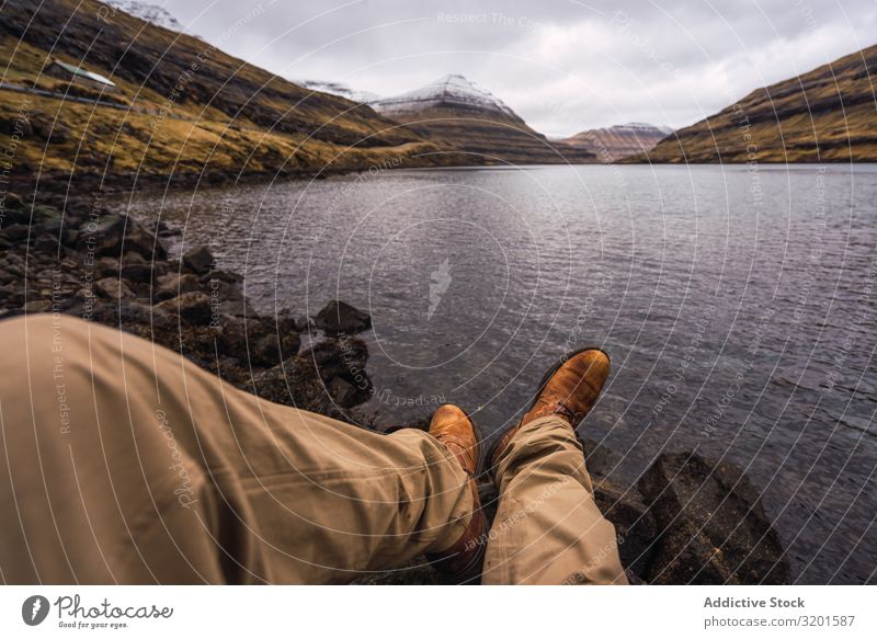 nicht erkennbare Person, die in der Nähe des Sees sitzt und Beine zeigt Mensch Pflanze Küste Wasser Felsen Stein Aussicht malerisch Ferien & Urlaub & Reisen