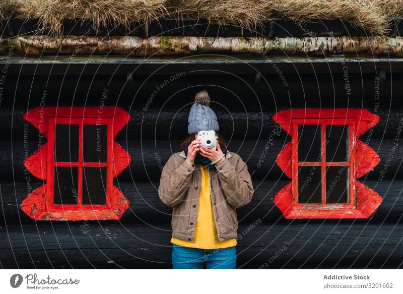 Frau in Winterkleidung vor einer Holzhütte beim Fotografieren attraktiv Freude Glück Berge u. Gebirge Fröhlichkeit Porträt Kaukasier Fotokamera Sommer Aussicht
