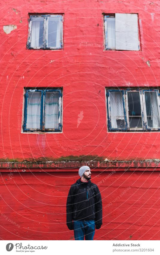 bärtiger Mann, der vor einem roten Gebäude auf der Färöer-Insel steht und weg schaut Model attraktiv gutaussehend schön ruhig Lifestyle sanft Jugendliche