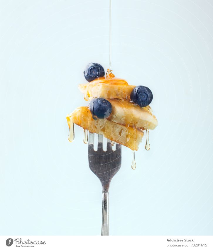 Appetitanregendes Obstdessert mit Honig auf der Gabel Dessert appetitlich Frucht Zusammensetzung süß Erdbeeren Blaubeeren aromatisiert weißer Hintergrund