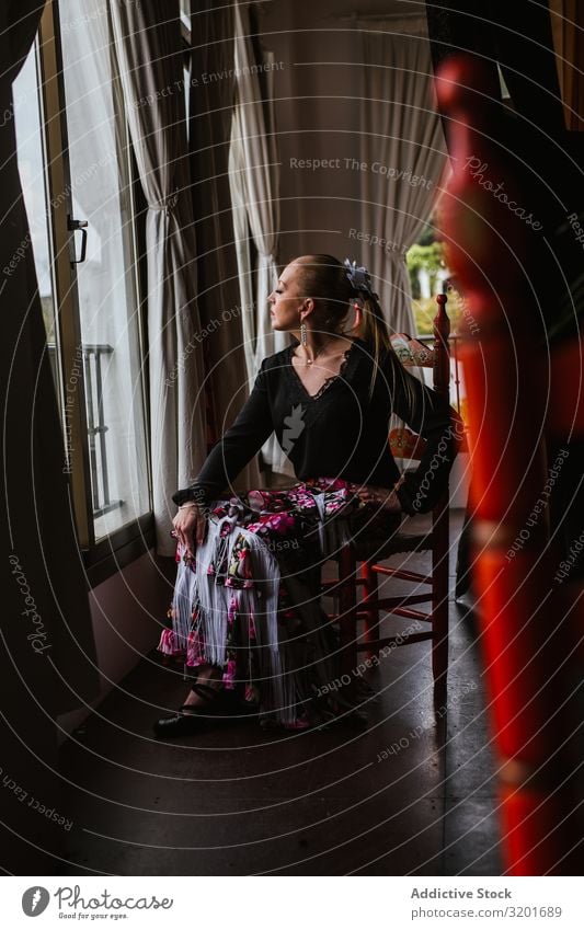 Flamenco-Tänzerin im Anzug, die sitzt und aus dem Fenster schaut Frau Kleid schön Ausdruck genießen Flamencotänzer attraktiv elegant Spanisch Tradition