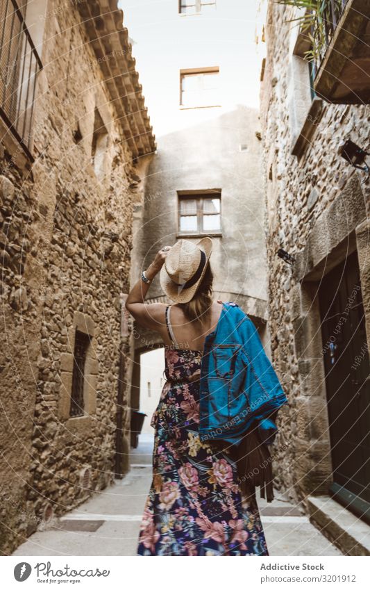 Frau, die auf einem schmalen Pfad in einem Dorf geht Mode Hut Lifestyle Außenaufnahme Mensch Straße Stil Sommer Europa Tourismus Tourist Stadt