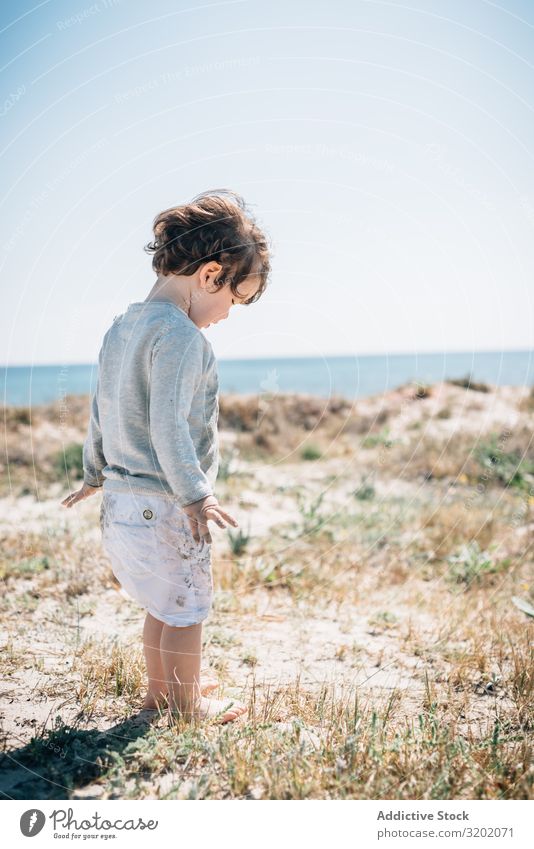 Barfuß-Kind in Kurzform barfuß am Sandstrand klein winken Strand Säuglingsalter niedlich Freude erkundend schön heiter Kindheit Fundstück hübsch reizvoll