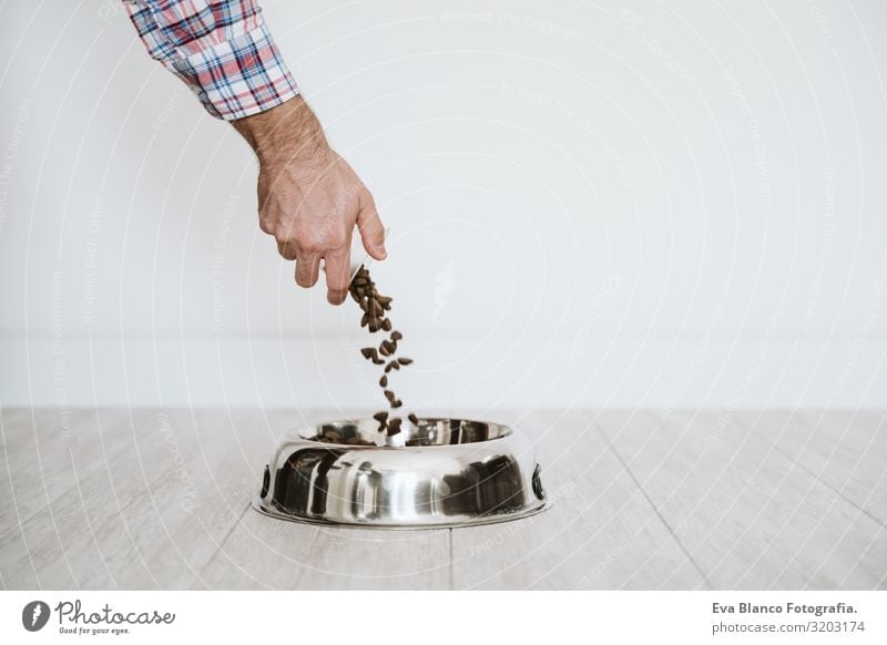 Mann füllt zu Hause mit der Hand einen Napf mit Hundefutter Mandat Lebensmittel Schalen & Schüsseln heimwärts regenarm Diät Tisch Welpe Nährstoff Haufen