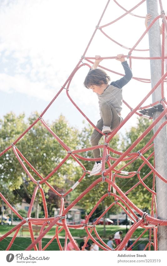 Junge auf Seilkletternetz im Sonnenlicht Spielplatz Tennisnetz Freizeit & Hobby besinnlich erhängen träumen klein Kind Kindheit Aktion spielerisch Klettern