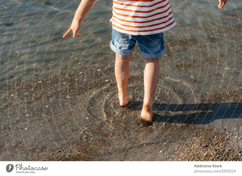 Verspielter kleiner Junge, der ins Wasser tritt seicht platschen Schritt spielerisch Sommer Ferien & Urlaub & Reisen Kind Freizeit & Hobby Spielen Meer Strand