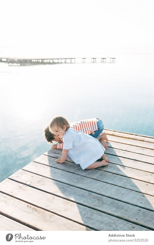 Neugierige Kinder am Pier seltsam Meereslandschaft Anlegestelle Zusammensein beobachten niedlich Baby Geschwisterkind Junge Mädchen charmant sitzen