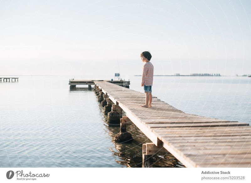 Einsames Kind am Pier bei Sonnenschein Junge Anlegestelle träumen Sommer Sonnenlicht Ferien & Urlaub & Reisen Kindheit Wasser Natur Freizeit & Hobby Ausflug