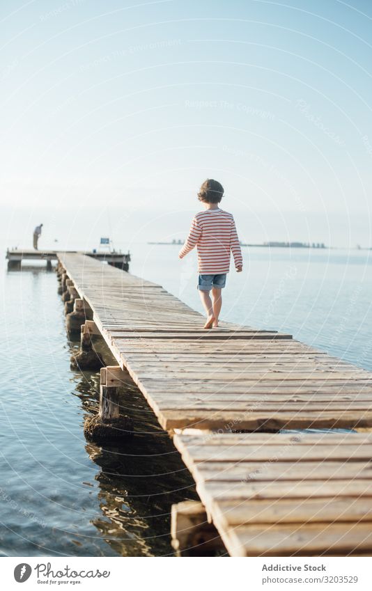 Einsames Kind am Pier bei Sonnenschein Junge Anlegestelle laufen träumen Sommer Sonnenlicht Ferien & Urlaub & Reisen Kindheit Wasser Natur Freizeit & Hobby