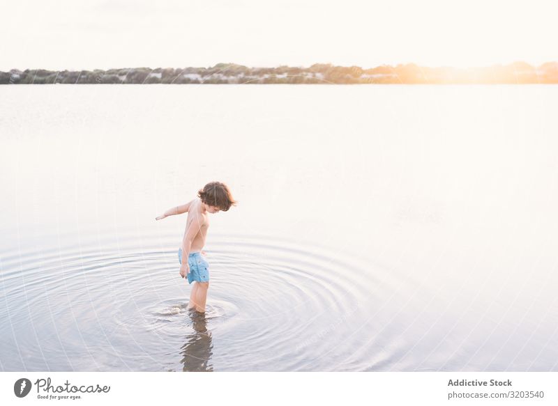 Junge geht im Wasser des Sees Strand Sommer erkunden laufen Kind Sonnenuntergang Kindheit Freizeit & Hobby Ferien & Urlaub & Reisen hell träumen Einsamkeit