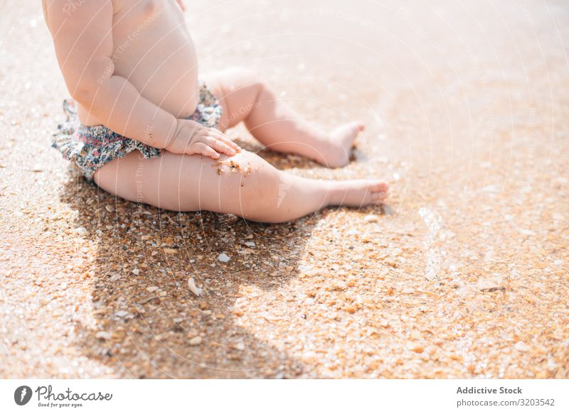 Scherenschnittansicht eines anonymen, süßen Babys, das am Strand sitzt reizvoll Sand winken niedlich Sommer Küste Freizeit & Hobby Freude Kind