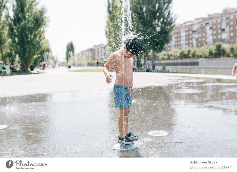 Kind steht in einem Springbrunnen auf der Straße Junge Düsenflugzeug Sommer Im Wasser treiben strömen Park Freude Ferien & Urlaub & Reisen Stadt stehen frisch