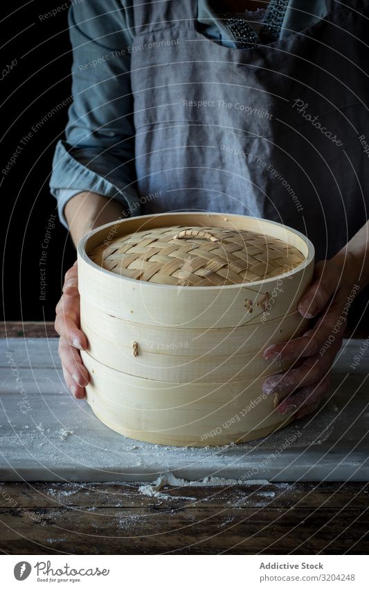 Person, die einen Bambus-Dampfer hält vereinzelt Dim Sum Küchengeräte Container Kasten Wasserdampf Utensil Korb Orientalisch Objektfotografie Deckel überdeckt