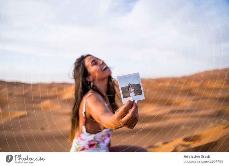 Glückliche Frau zeigt Sofortfoto in der Wüste Fotografie sofort Ferien & Urlaub & Reisen zeigen Marokko Freude heiter Schuss Grafik u. Illustration Selbst Zarge