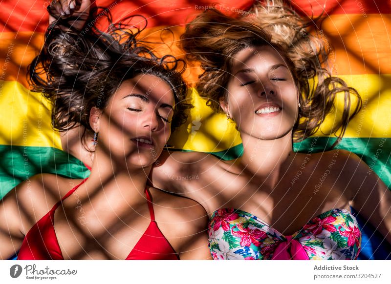 Lesbisches Paar auf Regenbogenfahne liegend Homosexualität lgbt Fahne geschlossene Augen lachen Frau Jugendliche Lifestyle Freizeit & Hobby ruhen Erholung Liebe