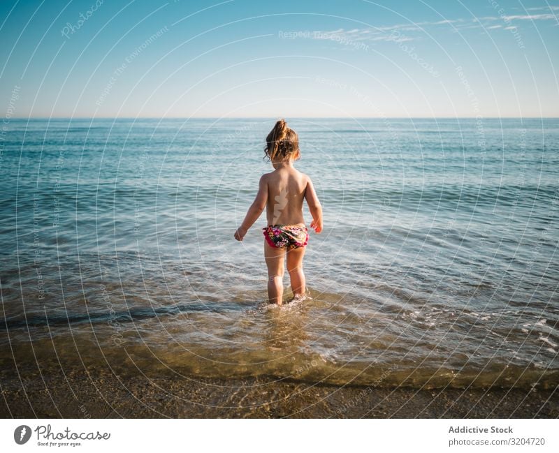 Rückenansicht eines Mädchens, das im Wasser der Küste steht Spielen Seeküste niedlich Kleinkind reizvoll Meer Badeanzug Wärme Strand Sonnenstrahlen Kindheit