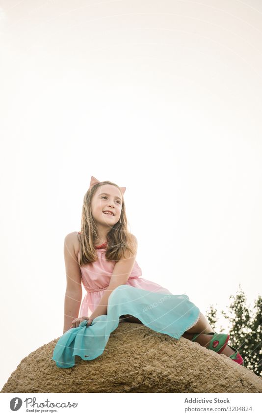 Verträumtes, süßes Mädchen auf einem Felsen sitzend träumen Natur Kind Sommer Kindheit niedlich Kleid schön Beautyfotografie Zeitgenosse erkunden unschuldig