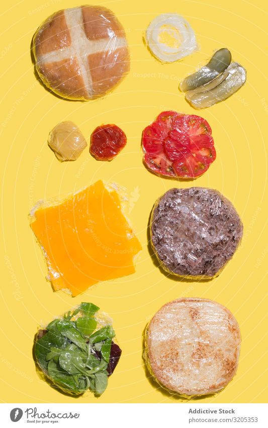 Zutaten eines in Plastik verpackten Cheeseburgers Grillen Rindfleisch Brot Brötchen Burger Käse Entwurf flache Verlegung Lebensmittel Hamburger Ketchup