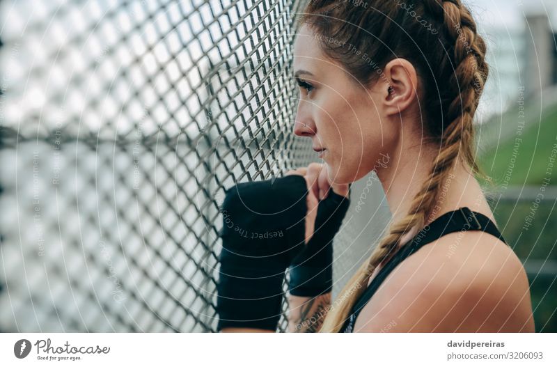 Sportlerin, die durch einen Zaun schaut. Lifestyle schön Körper Gesicht Freizeit & Hobby Mensch Frau Erwachsene Hand Wolken Handschuhe Fitness authentisch stark